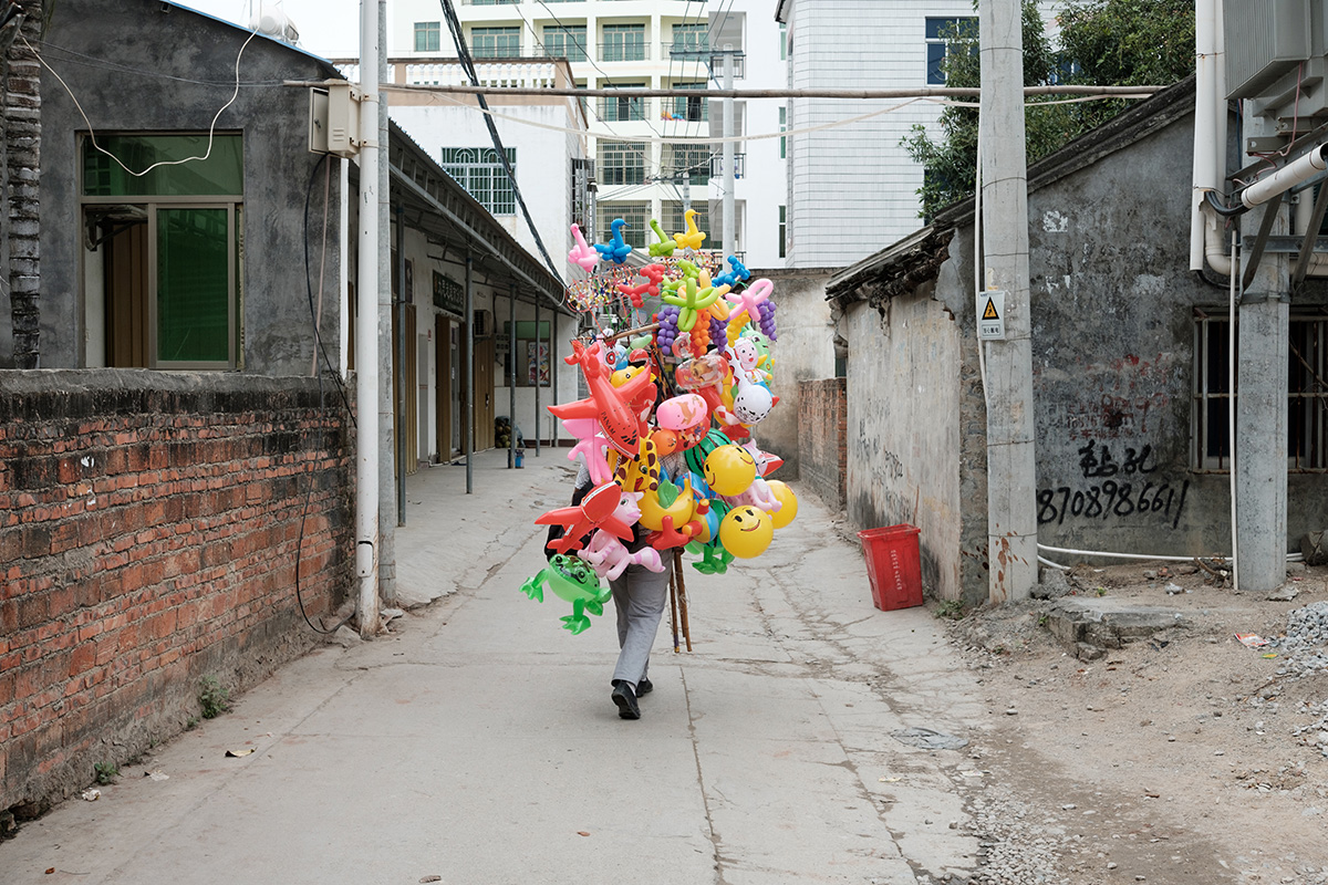 A holiday goods seller walks through the streets of Huixincun village, Hainan, China.